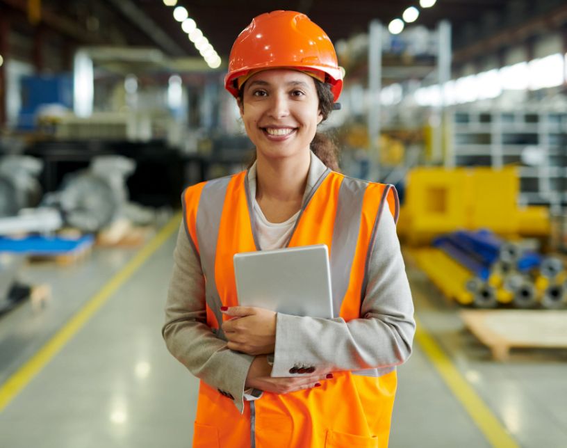 Woman with orange hard hat and safety vest holding an ipad.