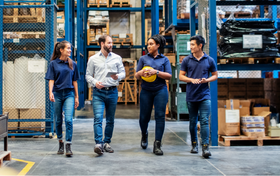 Group of men and women walking through a warehouse.   